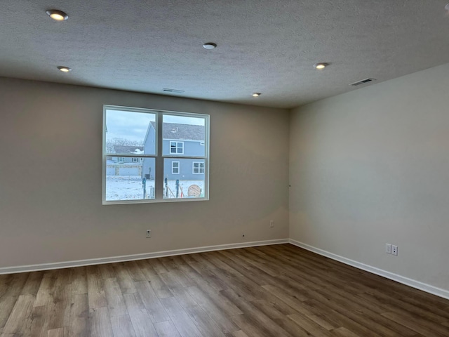 unfurnished room with hardwood / wood-style floors and a textured ceiling