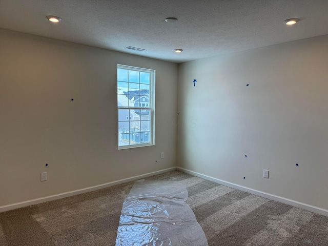 carpeted empty room featuring a textured ceiling