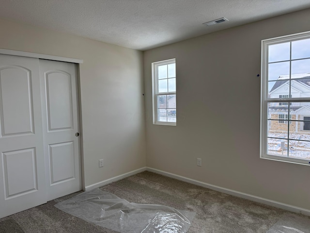 unfurnished bedroom with carpet floors, a closet, and a textured ceiling