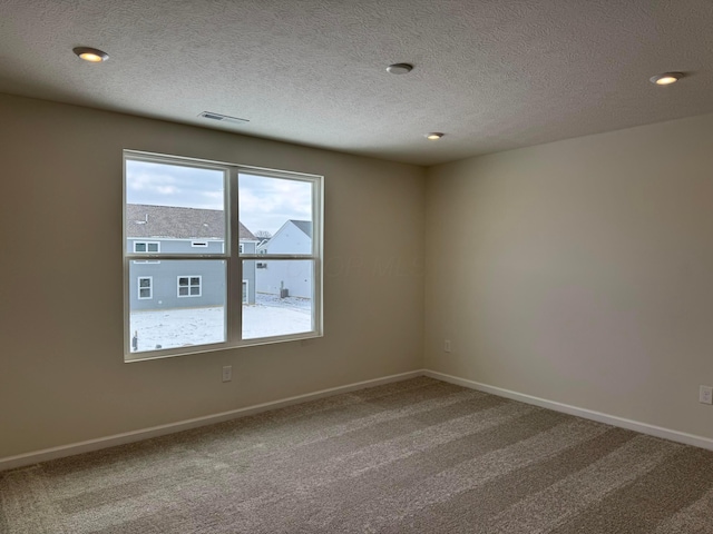 unfurnished room featuring a textured ceiling and carpet