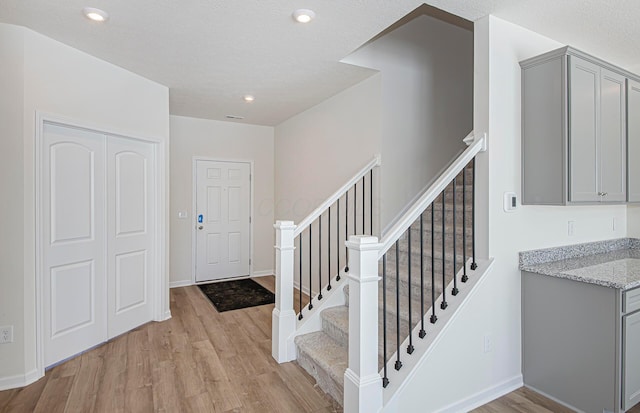 foyer with light wood-type flooring and a textured ceiling