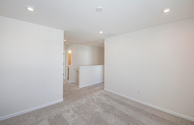 unfurnished room with light carpet and a textured ceiling