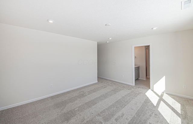 empty room with light carpet and a textured ceiling