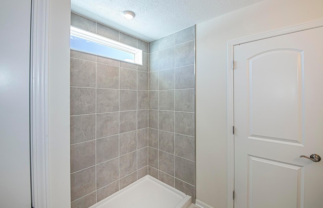 bathroom featuring a textured ceiling and tiled shower