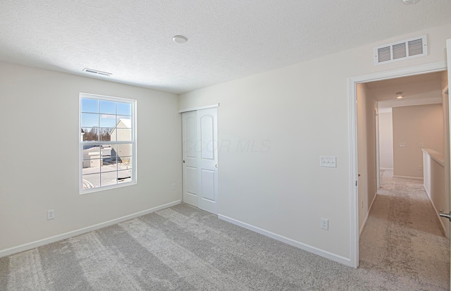 unfurnished bedroom with a textured ceiling and light colored carpet