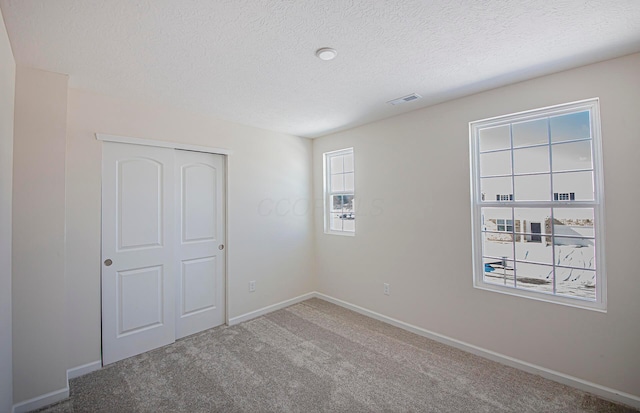 unfurnished bedroom with carpet floors, a closet, and a textured ceiling