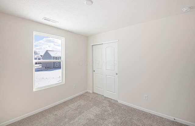 unfurnished bedroom featuring light carpet and a textured ceiling