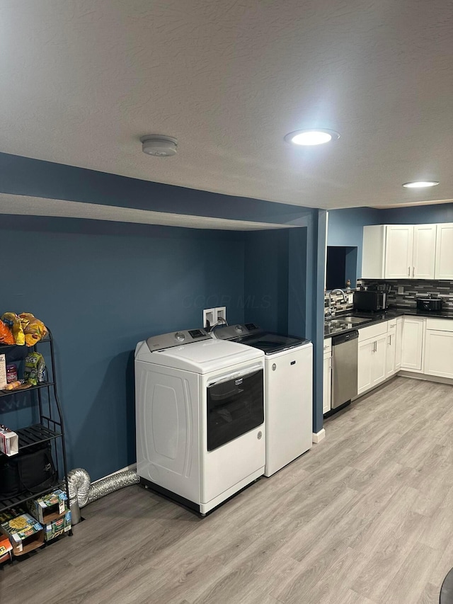 laundry area with washer and dryer, sink, and light hardwood / wood-style flooring