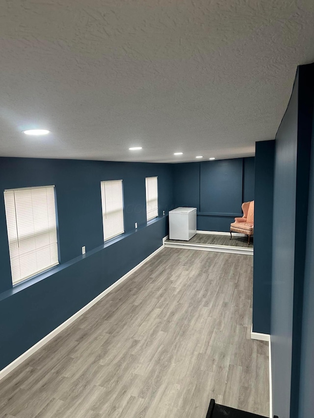 spare room with a textured ceiling and light wood-type flooring