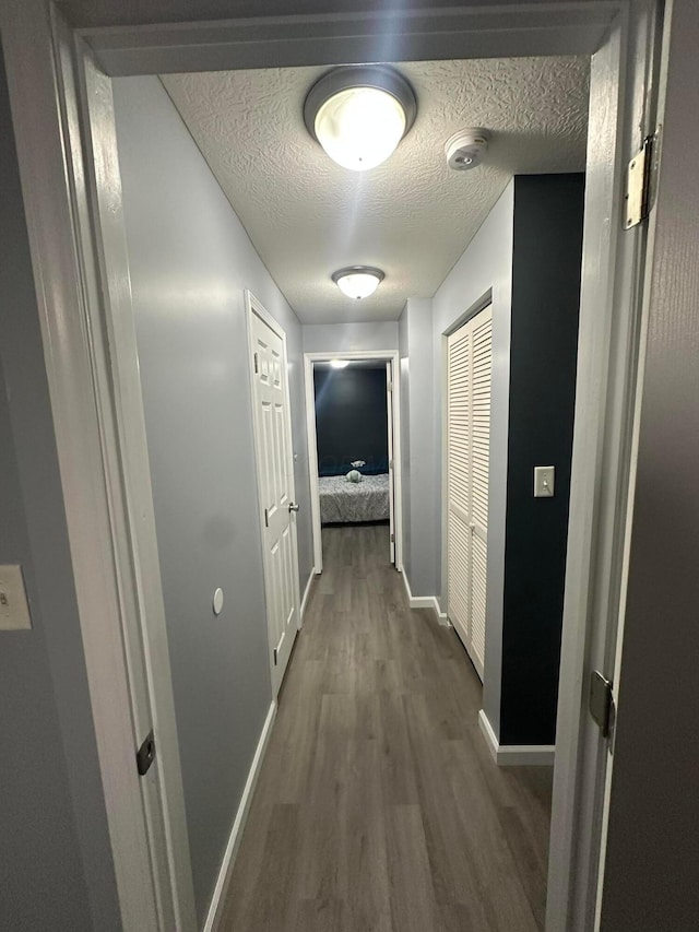 corridor with dark hardwood / wood-style flooring and a textured ceiling