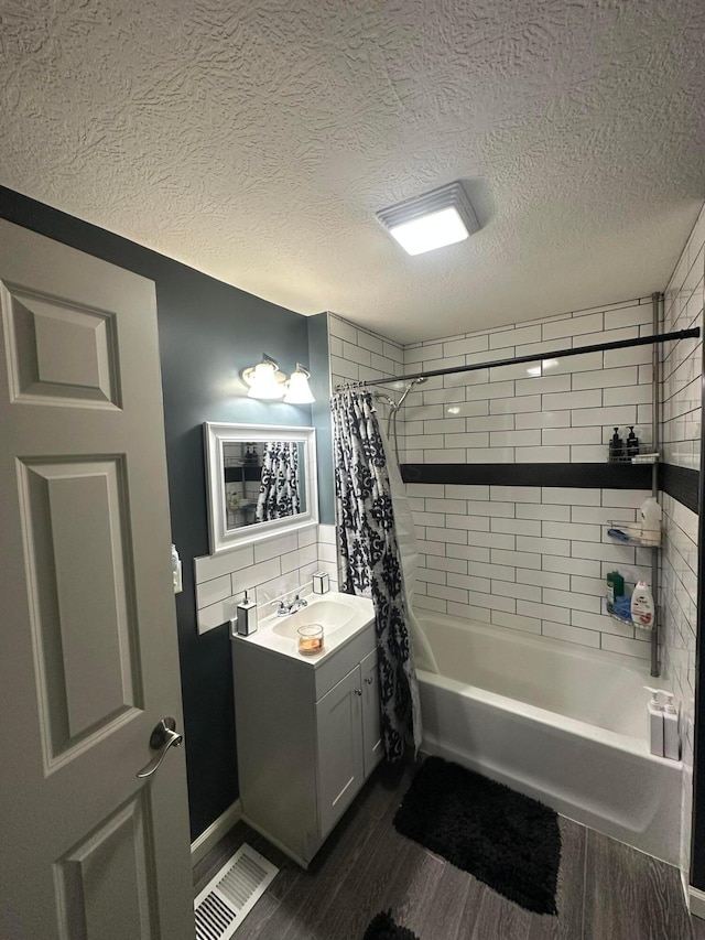 bathroom with shower / bath combination with curtain, wood-type flooring, a textured ceiling, and vanity