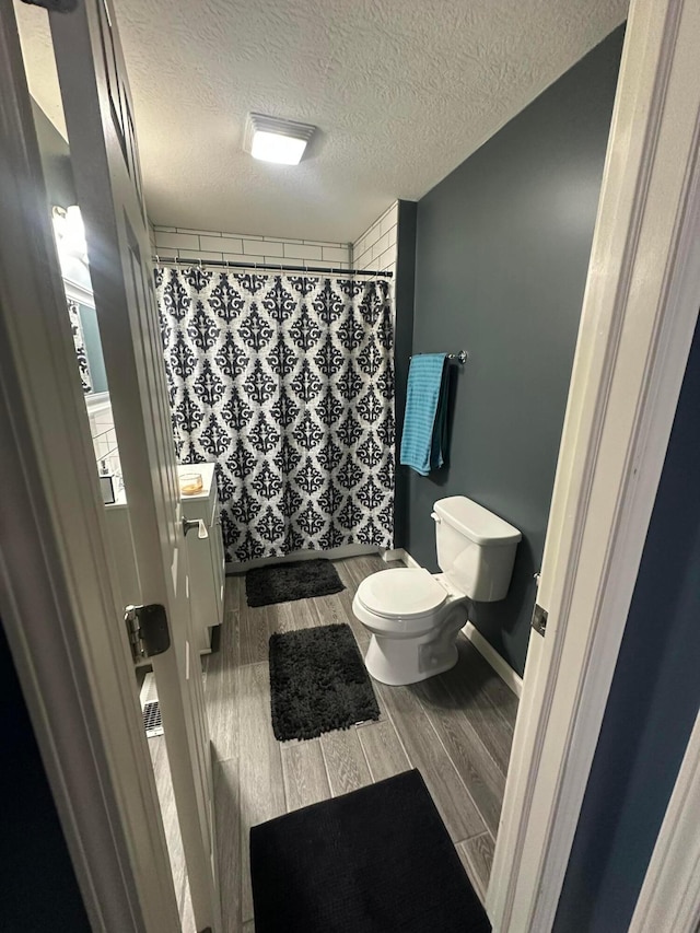 bathroom featuring vanity, a shower with curtain, hardwood / wood-style flooring, toilet, and a textured ceiling