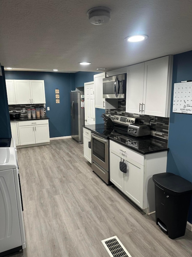 kitchen featuring washer / dryer, white cabinetry, and appliances with stainless steel finishes