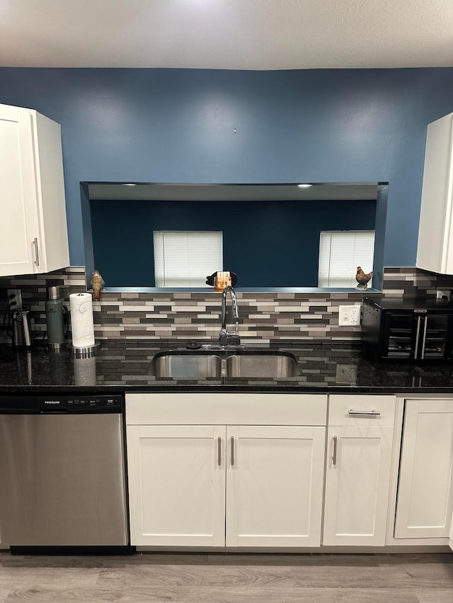 kitchen with light wood-type flooring, white cabinetry, stainless steel dishwasher, and sink