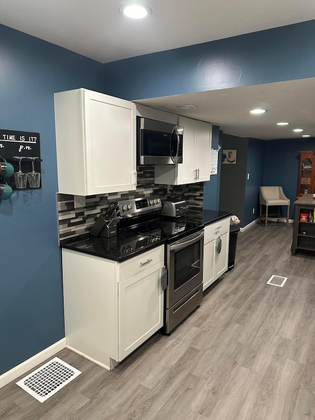 kitchen with decorative backsplash, white cabinetry, appliances with stainless steel finishes, and light hardwood / wood-style flooring