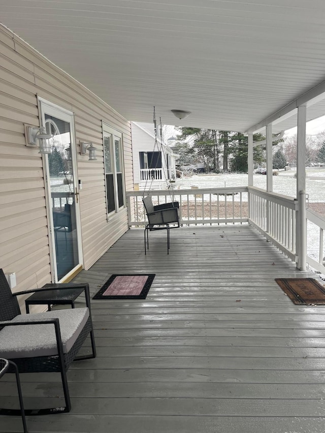 snow covered deck featuring a porch