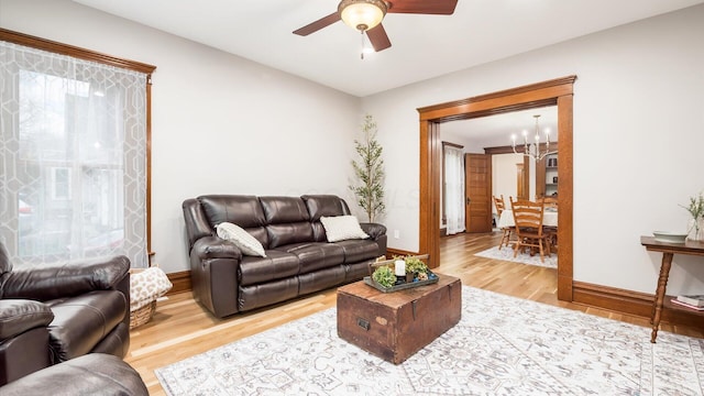 living room featuring ceiling fan with notable chandelier and hardwood / wood-style flooring