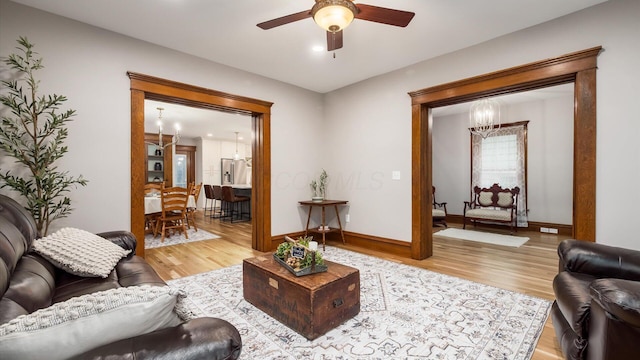 living room featuring ceiling fan with notable chandelier and light hardwood / wood-style floors