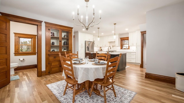 dining area featuring a notable chandelier, light hardwood / wood-style floors, and sink