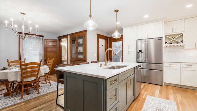 kitchen with white cabinetry, an island with sink, light hardwood / wood-style floors, gray cabinets, and appliances with stainless steel finishes