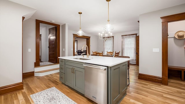 kitchen featuring pendant lighting, sink, stainless steel dishwasher, light wood-type flooring, and an island with sink