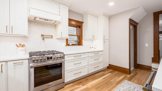 kitchen with white cabinets, light wood-type flooring, ventilation hood, and high end stainless steel range