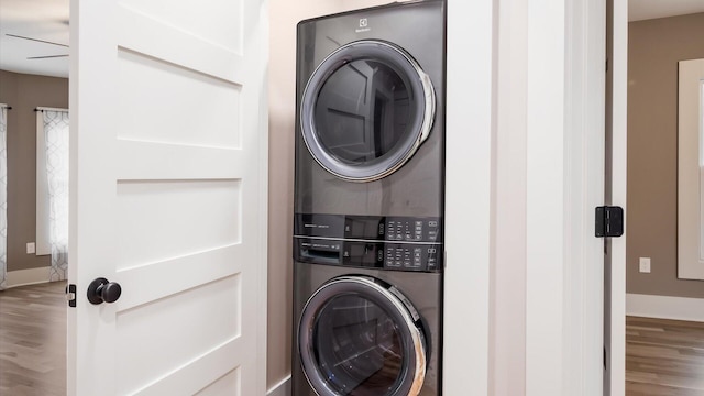 laundry area with wood-type flooring and stacked washer / drying machine