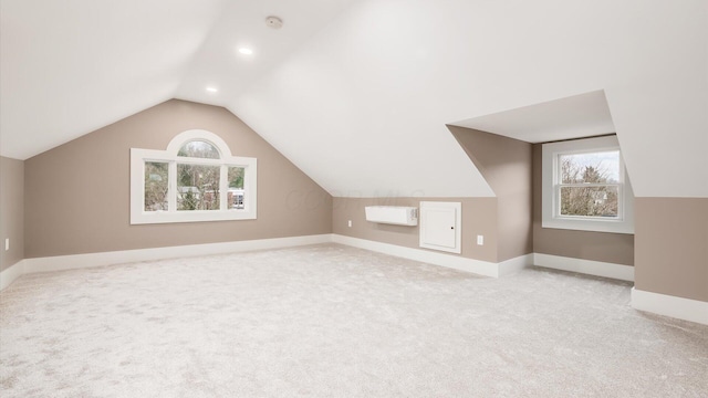 bonus room with light colored carpet and vaulted ceiling