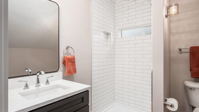 bathroom featuring toilet, vanity, and tiled shower