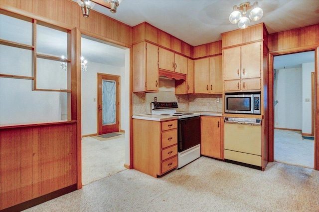 kitchen with light colored carpet, white appliances, backsplash, and wooden walls