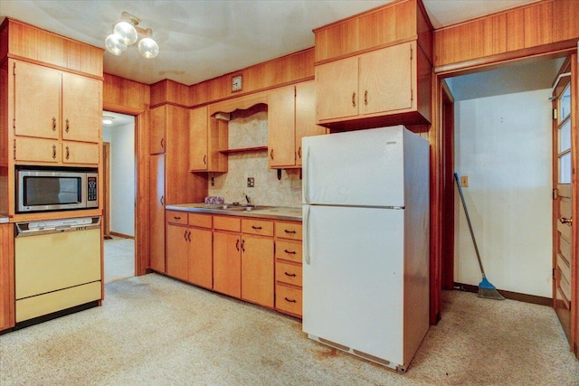 kitchen with white appliances, light colored carpet, wood walls, and sink