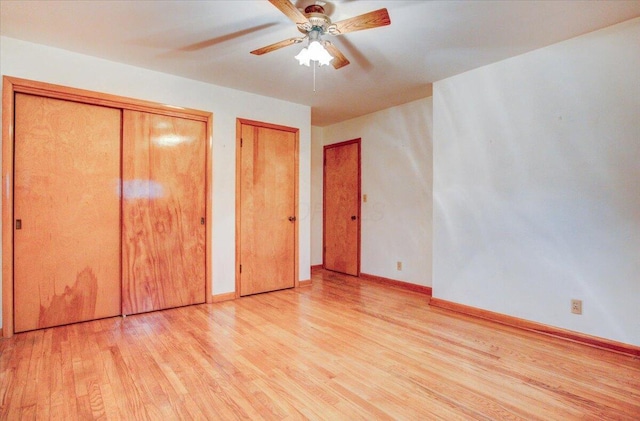 unfurnished bedroom with two closets, light hardwood / wood-style flooring, and ceiling fan