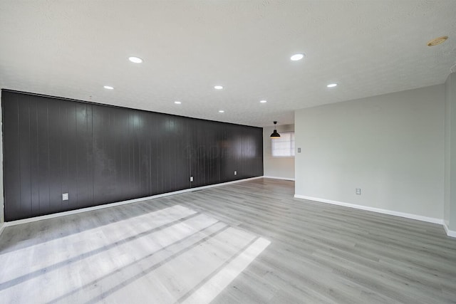 spare room featuring wood walls and light hardwood / wood-style floors