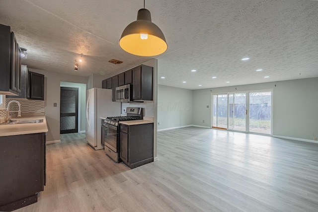 kitchen featuring light wood-type flooring, a textured ceiling, stainless steel appliances, dark brown cabinetry, and sink