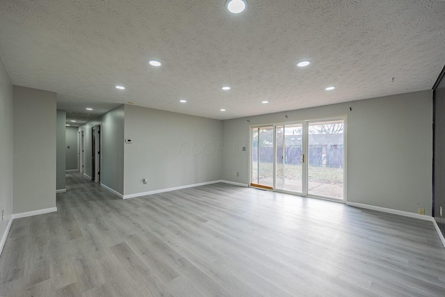 unfurnished room featuring a textured ceiling and light wood-type flooring