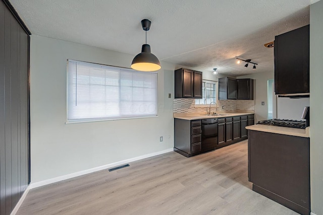 kitchen featuring pendant lighting, dishwasher, sink, decorative backsplash, and light wood-type flooring