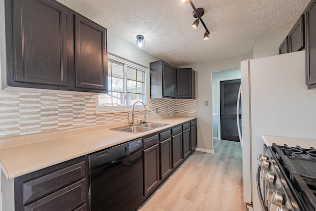 kitchen with sink, black dishwasher, light hardwood / wood-style floors, a textured ceiling, and decorative backsplash