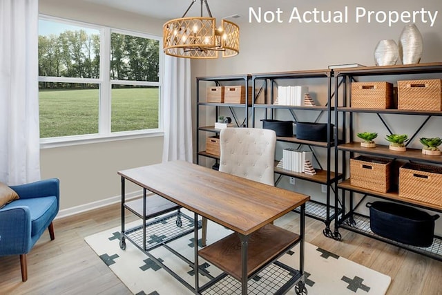 home office with wood finished floors, a wealth of natural light, and a notable chandelier