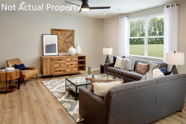 living area with light wood-style floors, ceiling fan, and baseboards