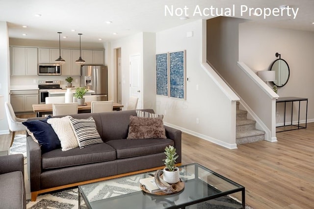 living area with light wood-type flooring, baseboards, stairway, and recessed lighting