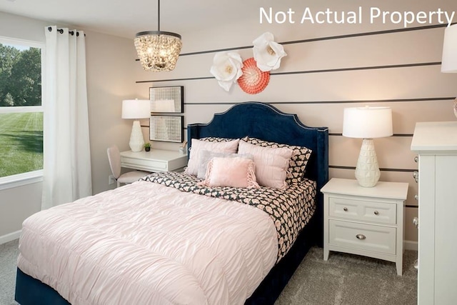 bedroom with dark colored carpet and a notable chandelier