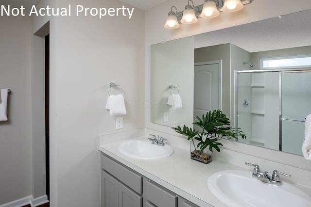 full bath with double vanity, a shower stall, and a sink