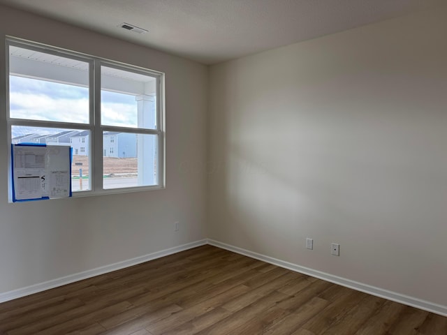 unfurnished room with visible vents, baseboards, and wood finished floors