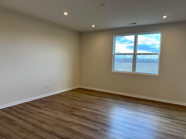 empty room with baseboards, dark wood-type flooring, visible vents, and recessed lighting