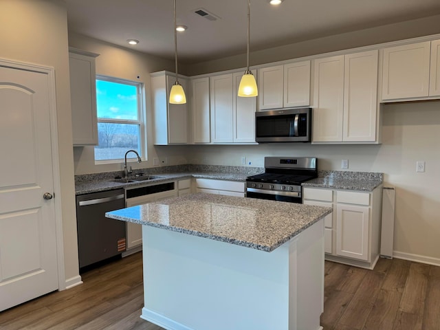 kitchen featuring visible vents, appliances with stainless steel finishes, light stone counters, dark wood-style flooring, and a sink