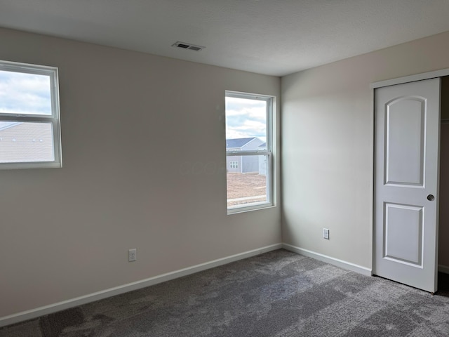 unfurnished room featuring carpet, a textured ceiling, visible vents, and baseboards