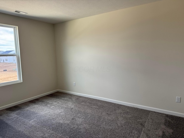 unfurnished room featuring baseboards, visible vents, dark carpet, and a textured ceiling