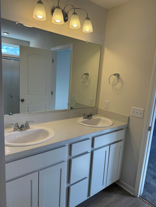 bathroom featuring double vanity, baseboards, a sink, and wood finished floors