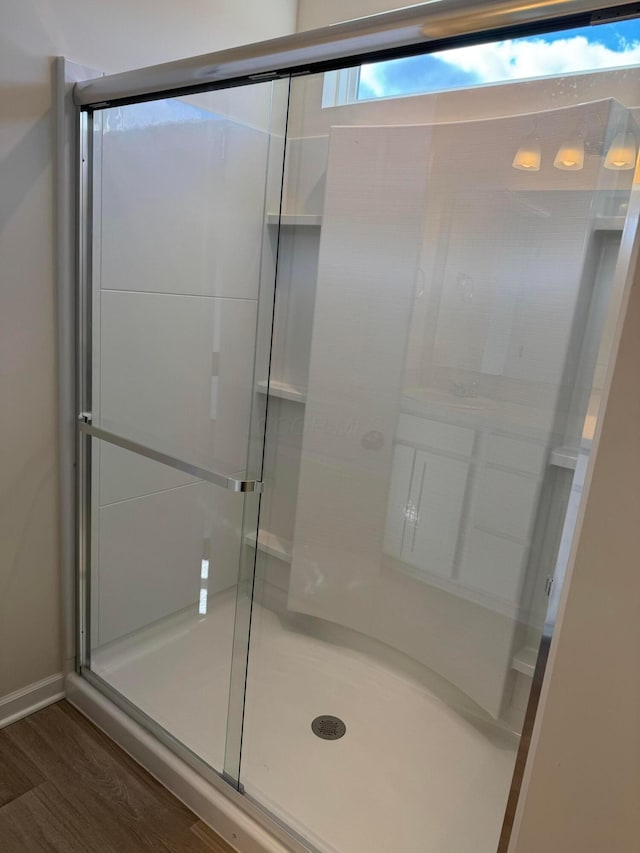 full bath featuring wood finished floors and a shower stall