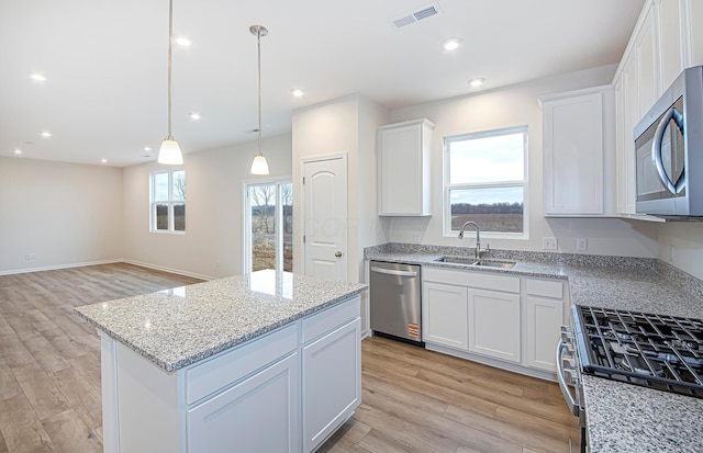 kitchen featuring appliances with stainless steel finishes, light wood-style flooring, a sink, and visible vents